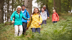 Multi generation family walking downhill on a trail in a forest during a camping holiday, Lake District, UK